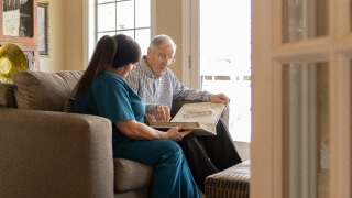 Our process hero image male client and caregiver sitting looking through a book