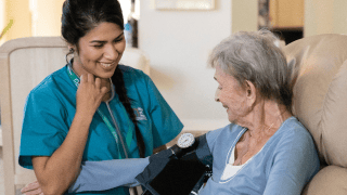 A caregiver takes her client’s blood pressure in a comfortable home.